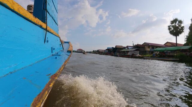 View of the Floating Village with a blue boat moving through the water in Kampong Khleang, Siem Reap, Cambodia.