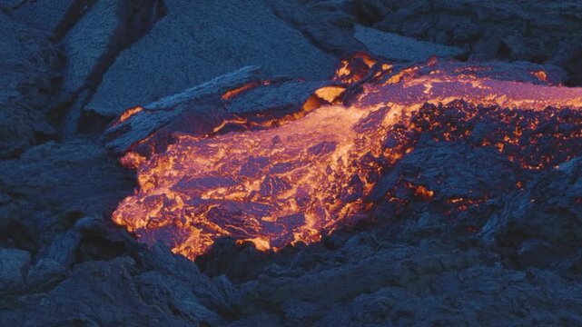 View of molten lava flowing over dark volcanic rock in Reykjanesbaer, Iceland.