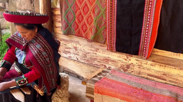 Peruvian woman artisan from Cuzco using a backstrap loom to create a colourful alpaca wool fabric
