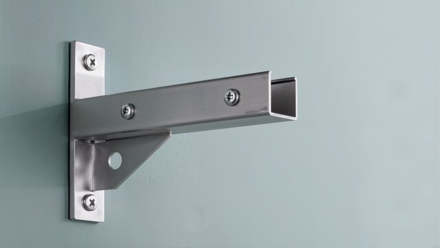 Close-up of a metal mounting bracket attached to a wall. Heavy duty steel hardware fixture with screws and support gusset