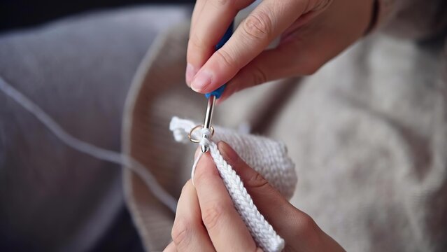 Person sewing white fabric with needle and thread in hands