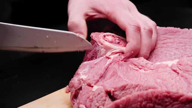 Person slicing pink ice cream with a knife on a wooden board