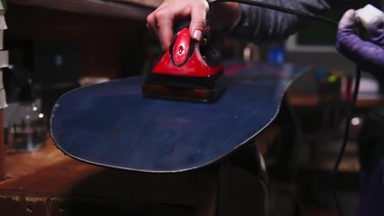 Person using an iron on a dark skateboard in a workshop © dumiceava
