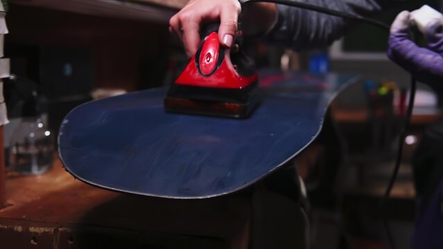 Person using an iron on a dark skateboard in a workshop