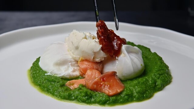 Poached egg on green sauce with tomatoes on a white plate