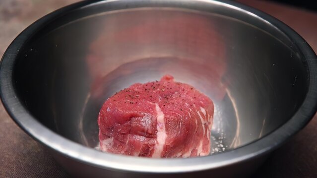 Raw beef steak in a metal slow cooker or rice cooker