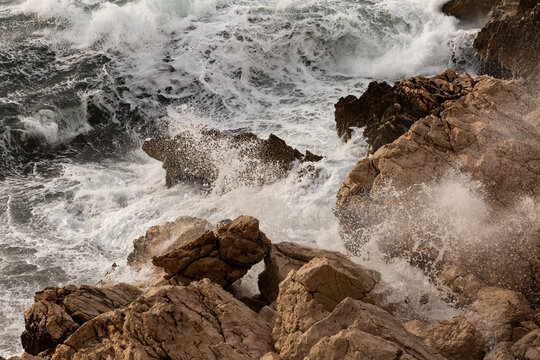Gros plan sur des vagues qui se brisent et qui s&rsquo;&eacute;crasent sur des gros rochers bruns, mer d&eacute;chain&eacute;e, &eacute;clats, vagues explosives, &eacute;cume blanche