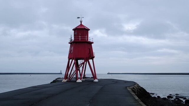 Atmospheric time-lapse of the iconic red Herd Groyne Lighthouse in South Shields as dark, moody clouds speed across the sky.