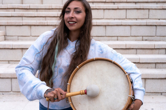 Young woman smiling holding bombo drum outdoors
