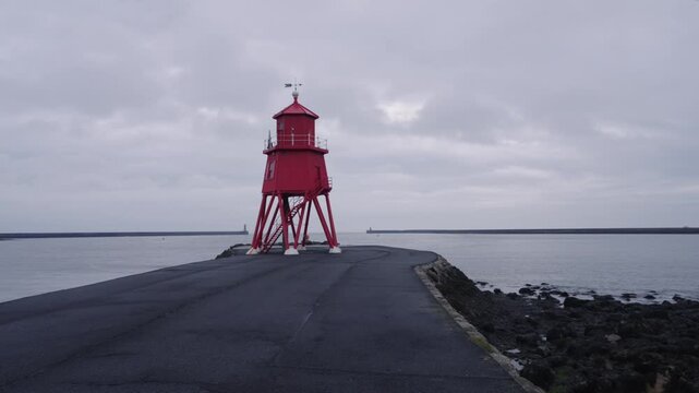 Atmospheric time-lapse of the iconic red Herd Groyne Lighthouse in South Shields as dark, moody clouds speed across the sky.