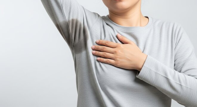 Woman showing visible underarm sweat stains on her grey shirt, highlighting a common perspiration problem or hyperhidrosis concern.