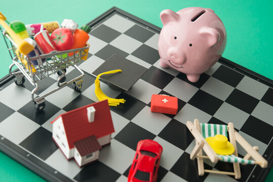 Piggy bank and many expense such as home mortgage loan, fuel, medical, car, education, foods, travel on chessboard. Cost of living rising in inflation or economy crisis, home finance and so on concept