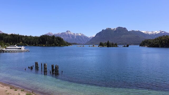 View of calm blue waters of Nahuel Huapi Lake with Isla Victoria, surrounded by snow-capped Andean mountains and forests San Carlos de Bariloche, Rio Negro Province, Argentina.