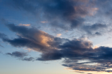 Fototapeta premium Evening clouds in motion, illuminated by fading sunlight
