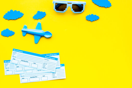 Sample of airplane ticket. Family trip with kid. Airplan toy and paper clouds. Yellow background flat lay space for text