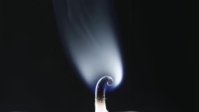 Close-up of a candle wick burning with smoke rising gracefully. Represents tranquility, ambiance, and the essence of relaxation
