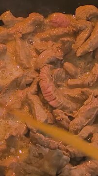 Covered pan with fried meat. Fried meat cooking steps including covering pan in kitchen setting