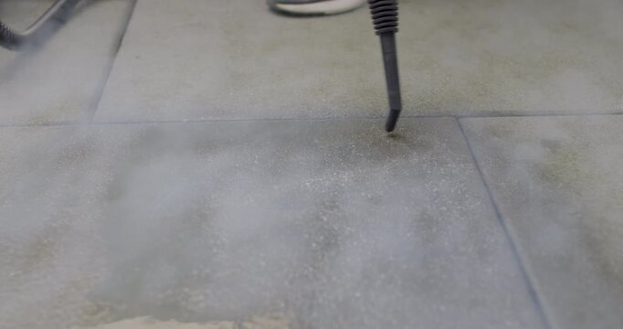 Close up view of professional high pressure steam tool nozzle spraying vapor on dirty tile grout