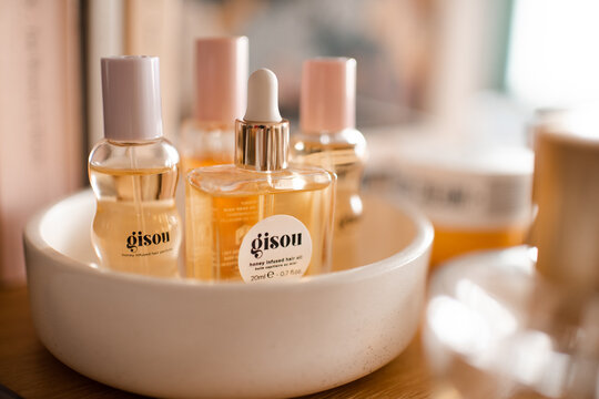 Paris, France - 23 of June 2026: Gisou beauty products in glass bottles. Hair oil and mist perfume on bed table.