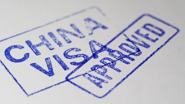 Macro video frame of a stamp pressing "APPROVED" onto a China visa document.