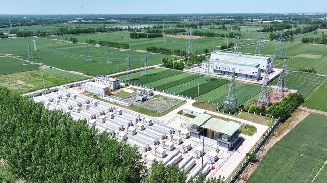 Aerial view of a large-scale energy storage station adjacent to farmland and wind power infrastructure