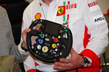 Naklejka premium Mugello, Italy - November 28, 2007: An unknown man holds a modern Formula 1 steering wheel during the 2007 Ferrari World Finals.