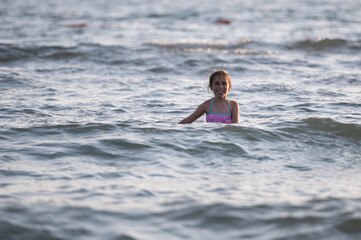 Fototapeta premium Happy child smiling in ocean water during summer vacation