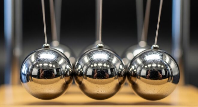 Shiny Metal Newtons Cradle Balls Aligned in Motion on Wooden Base