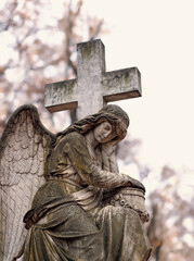 Obraz premium fragment old monument of angel with cross on cemetery. symbol of religion, faith in God, resurrection, memory, eternity. all saints day. Design for condolences, mourning card, obituary.