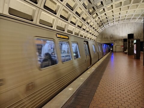 Washington, D.C., USA &ndash; March 3, 2025: A subway train is captured in motion, causing its front end to be slightly blurred. Vertical black information pylons are installed on the platform