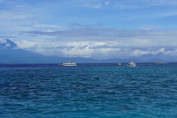 Obraz premium Luxury Boats on Blue Bali Sea with Mountain Landscape and Dramatic Cloudy Sky, Indonesia