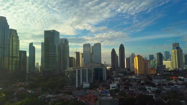 Wide aerial drone shot of Jakarta's central business district at sunrise with blue sky