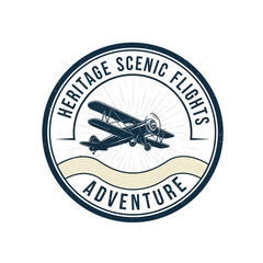 Vintage aviation logo with biplane silhouette for scenic flight services. © Stylee