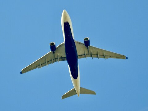 the bottom of a plane flying in the air with a blue sky