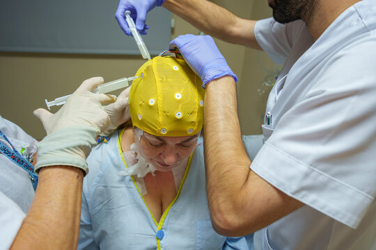 Medical professionals fitting an eeg cap and electrodes to ready a patient for brain activity monitoring