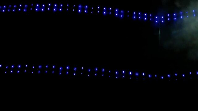 Two parallel rows of glowing blue string fairy lights hanging against a pitch black night background