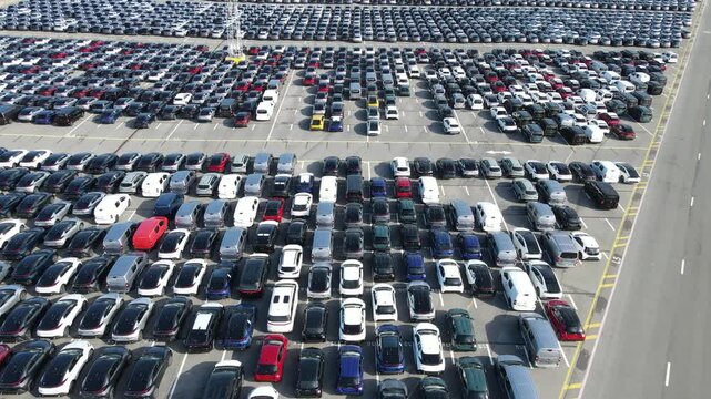 Close drone glide moves above repeated blocks of parked premium SUVs.