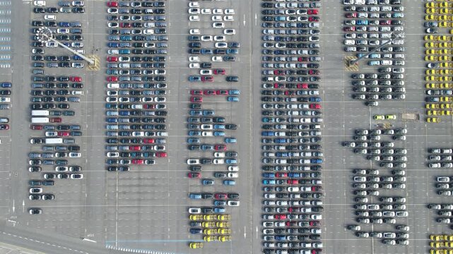 Straight down drone view shows new cars arranged in repeating twelve row blocks.
