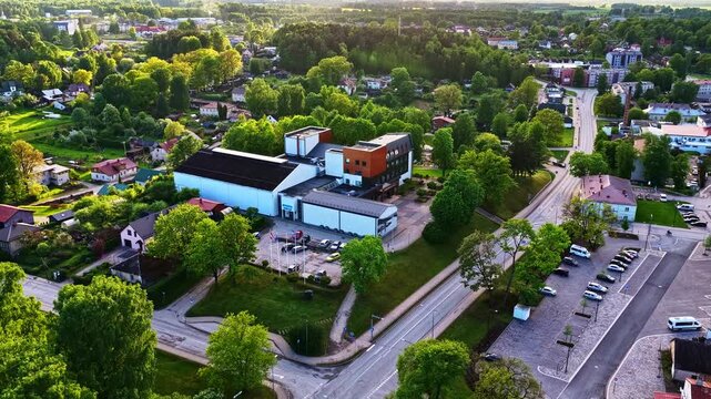 Aerial view of a modern building surrounded by lush green trees in a small European town