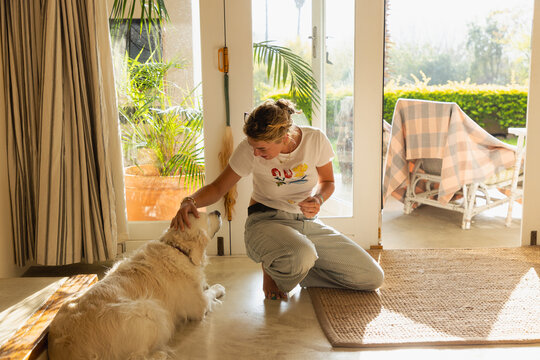 young woman playing with her English cream golden retriever dog at home