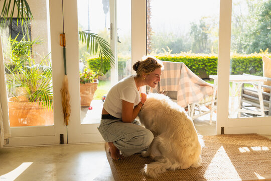 young woman playing with her English cream golden retriever dog at home