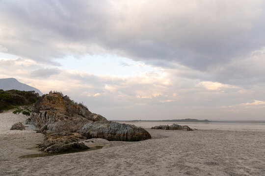 low tide at rocky coastline of Grotto Beach, Hermanus, South Africa at dusk