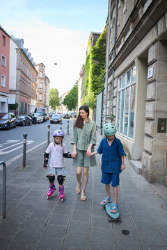 Mother and children enjoy a sunny day with outdoor activities on a city street