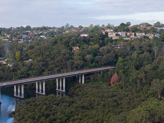 Naklejka premium Aerial view of river, bridge, and tree in the morning.