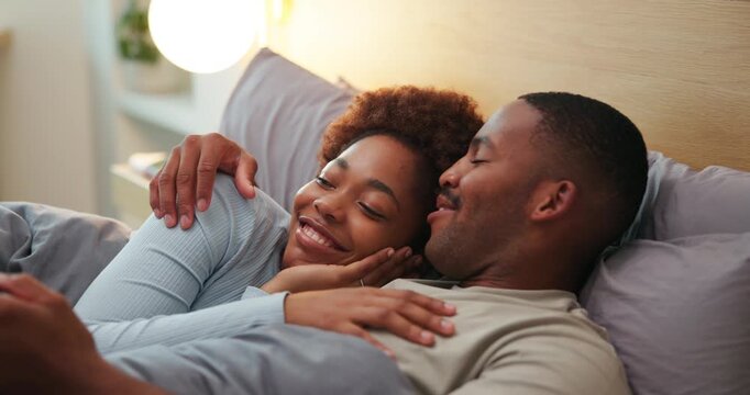 Happy couple, kiss and cuddle on bed, home and bonding with partner in bedroom, love and connection. Black people, smile and resting with spouse in house, affection and commitment for relationship