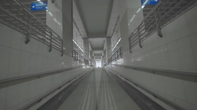 Modern pedestrian underpass leading to railway platform in station architecture.