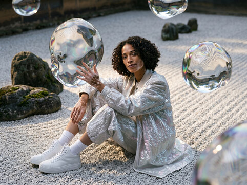 Woman Playing with Iridescent Soap Bubbles in Zen Garden