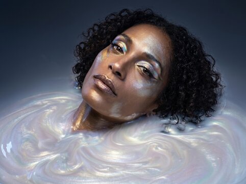Woman Submerged in Iridescent Water with Serene Expression