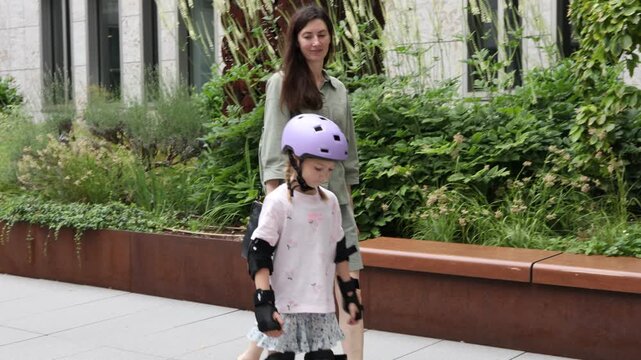 Child learning to skate with protective gear in a garden setting