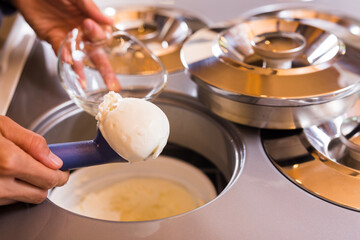 Fototapeta premium scoop of creamy ice cream in spoon from the refrigerator container